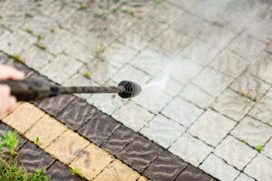 Close up photo of a man hands, cleans a tile of grass in his yard. High pressure cleaning.