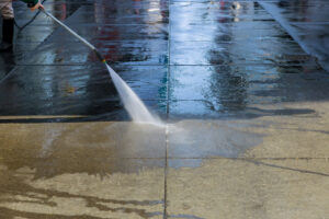 Worker washes the pavement asphalt in pedestrian zone on big modern city